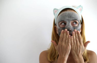 Köpüren maske ve kömür oksijeni güzel bir kadının yüzündeki ürünü temizliyor. Cilt bakım maskesi. Kulaklıklı komik kafa bandı