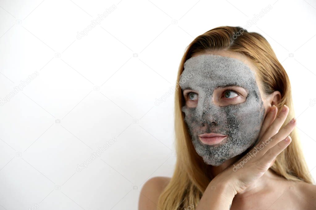 Bubbling mask with charcoal oxygen purifying product on the face of beautiful woman. Skin care mask. Funny headband with ears