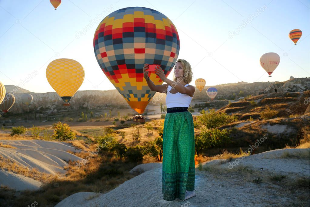 Beautiful happy girl traveller enjoying sunrise and balloon flight in Cappadocia Turkey. Freedom lifestyle.