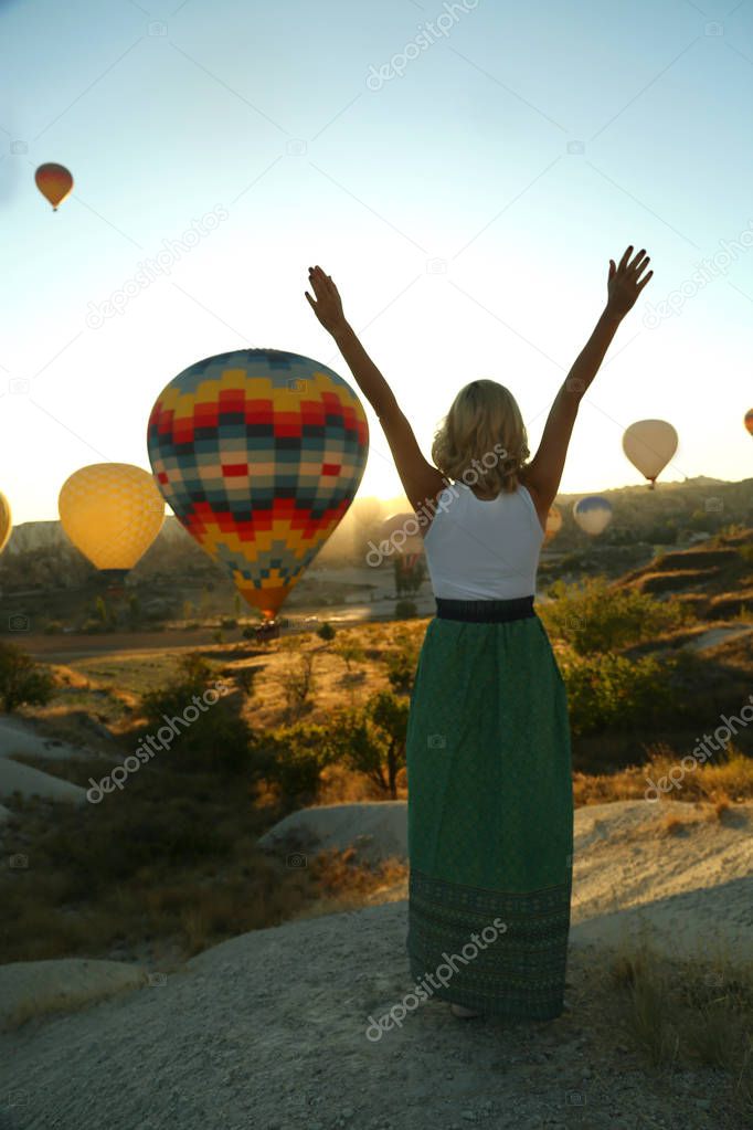 Beautiful happy girl traveller enjoying sunrise and balloon flight in Cappadocia Turkey. Freedom lifestyle.