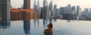 Genç mutlu kız Malezya 'daki Kuala Lumpur' da sabahın erken saatlerinde çatıdaki sonsuz havuzda tek başına yüzüyor..