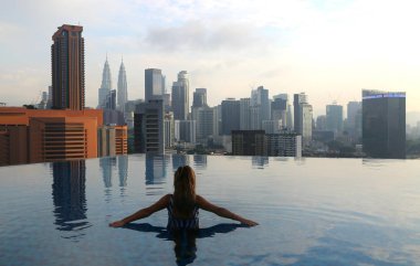 Genç mutlu kız Malezya 'daki Kuala Lumpur' da sabahın erken saatlerinde çatıdaki sonsuz havuzda tek başına yüzüyor..