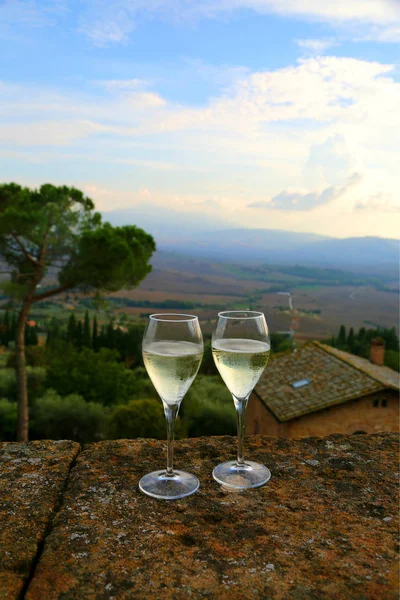 Two glasses of sparkling wine prosecco champagne on the balcony with famous Tuscany landscape view. Italian Tuscany background.