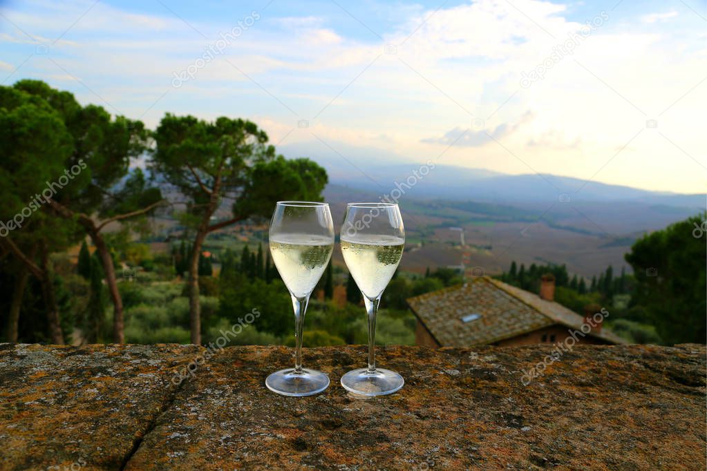 Two glasses of sparkling wine prosecco champagne on the balcony with famous Tuscany landscape view. Italian Tuscany background.