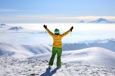 Sarı kayak ceketli mutlu kadın elleri tegenis dağının tepesinde duruyor. Ararat dağının görüntüsü.