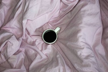 Pembe çarşaflı sabah kahvesi kupası. Pamuk tekstil el salladı. 