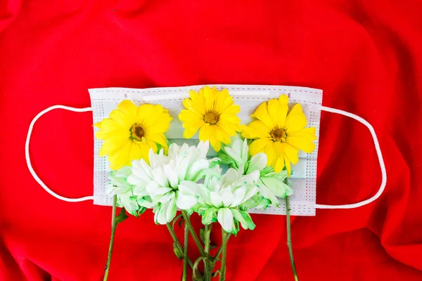 Flowers laying in the face mask on white background. Spring time allergy concept.