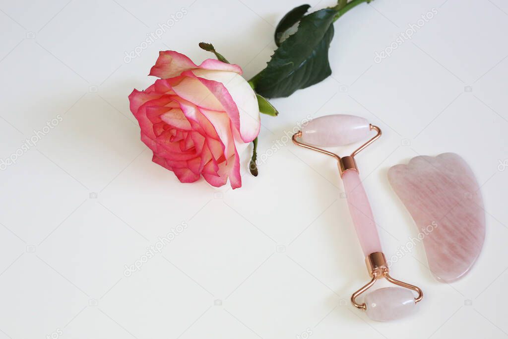 Face roller beauty device on white background. Pink facial roller for skin care. Face treatment tools.