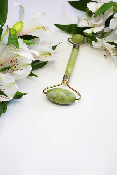 Face roller facial skin care luxury beauty tool.  Close up view of green face roller. Beauty tools. Vertical photo.