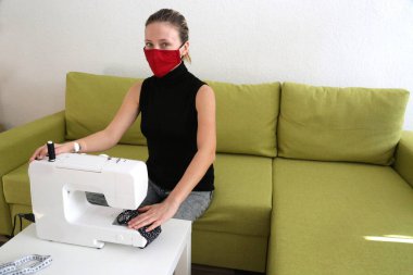 Evde korona virüsüne karşı korunmak için maske takan bir kadın. Covid 19 virüsüne karşı el yapımı koruyucu maske. DIY maskesi,