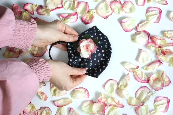 Handmade DIY cotton face mask on floral white background. Coronavirus preventive cloth textile mask.  Stylish decorated face mask.