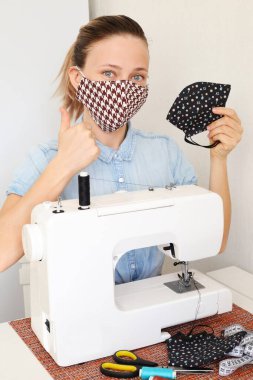 Evde korona virüsüne karşı korunmak için maske takan bir kadın. Covid 19 virüsüne karşı el yapımı koruyucu maske..