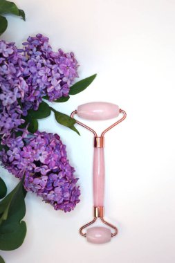 Beyaz arka planda cilt tedavisi için pembe kuvars yüz masajı. Ev spa ayarları.