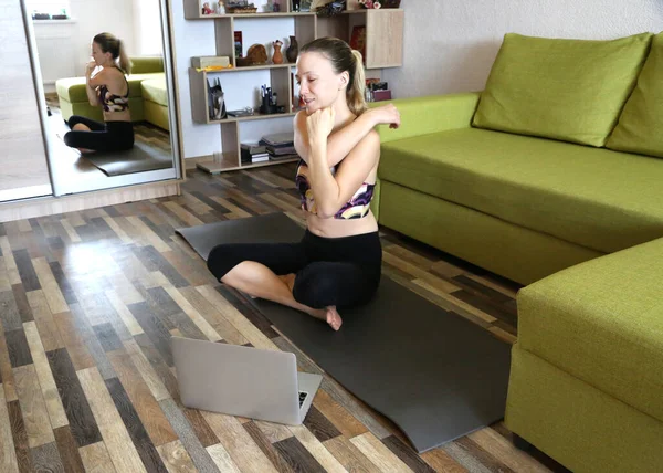 Woman doing yoga at home with laptop internet on line courses. Sportive and healthy lifestyle. Practice yoga during quarantine and self isolation.
