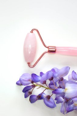 Beyaz arka planda cilt tedavisi için pembe kuvars yüz masajı. Ev spa ayarları.