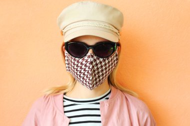 Dekoratif aksesuar olarak el yapımı pamuklu yüz maskesi takan genç bir kadın. Moda endüstrisinde popüler trend. Yeniden kullanılabilir yüz maskesi.