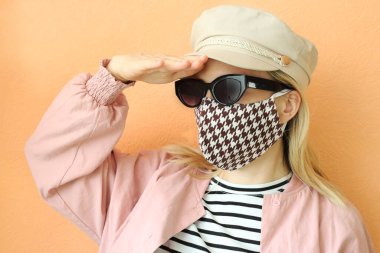 Dekoratif aksesuar olarak el yapımı pamuklu yüz maskesi takan genç bir kadın. Moda endüstrisinde popüler trend. Yeniden kullanılabilir yüz maskesi.