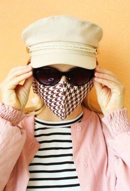Dekoratif aksesuar olarak el yapımı pamuklu yüz maskesi takan genç bir kadın. Moda endüstrisinde popüler trend. Yeniden kullanılabilir yüz maskesi.