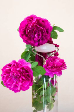 Çiçekli arka planda pembe kuvars silindiri. Spa ayarları. Yaşlanmayı önlemek için deri silindiri. Güzellik aletleri.