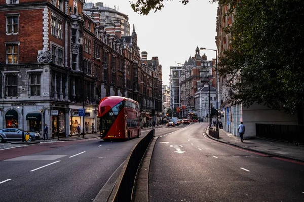 Hermosa toma de una escena de la ciudad con hermosos edificios y un autobús rojo acercándose a la estación —  Fotos de Stock