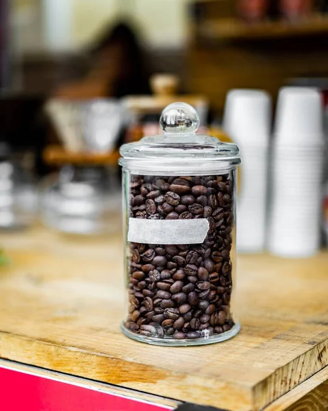 A vertical shot of a container full of coffee beans on a wooden table