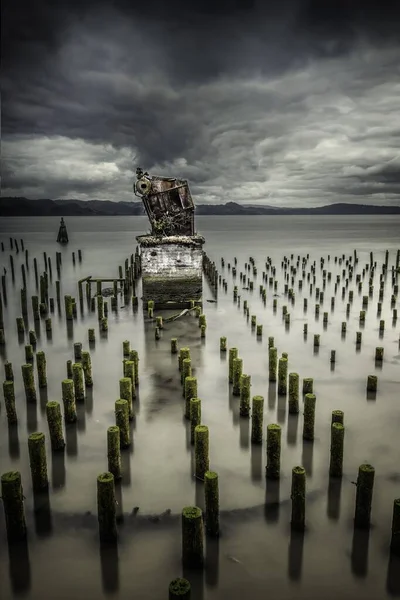 Une jetée abandonnée avec des planches de bois et un mécanisme métallique détruit sur une structure en pierre — Photo