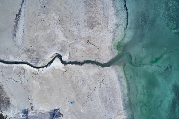 Plan grand angle d'une grosse fissure sur le rivage pierreux à côté de l'eau turquoise — Photo