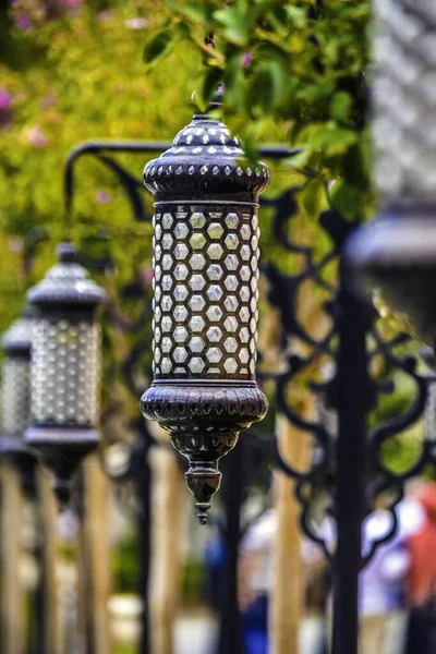 Vertical shot of a street lantern with beautiful patterns on a blurred green background — ストック写真