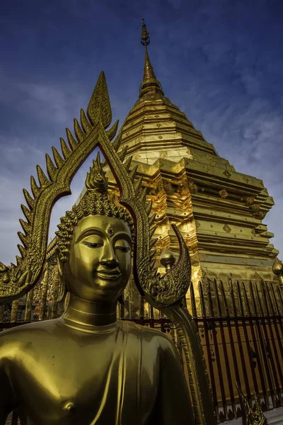 Красивый снимок золотой статуи Будды перед храмом под захватывающим небом — стоковое фото