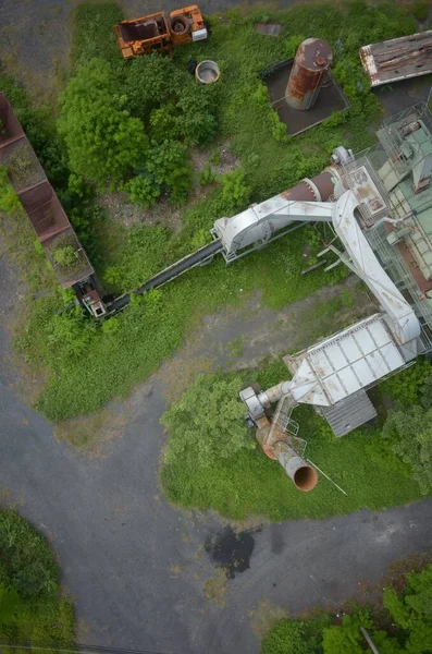 一座废弃工厂的垂直高角拍摄，工厂生长着明亮的绿色植物 — 图库照片