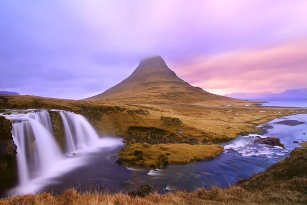 Rompiendo el disparo de una cascada que fluye por el río junto a una colina. — Foto de Stock