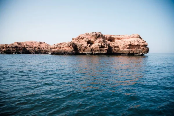 Una Isla Rocosa Medio Del Mar Tranquilo Bajo Cielo Azul — Foto de Stock