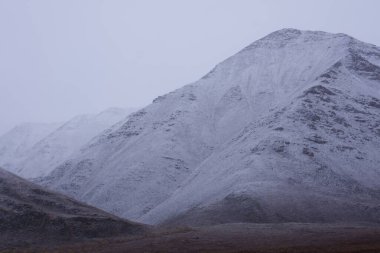 A low angle shot of snowy mountains covered in fog in the Gates of the Arctic National Park clipart