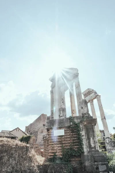 Vertical tiro de baixo ângulo de ruínas do edifício antigo sob os raios de sol brilhantes — Fotografia de Stock