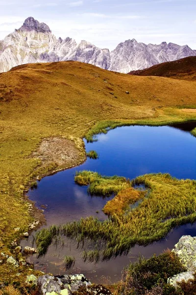 Tiro vertical de um lago azul brilhante em um vale amarelo e rochas no fundo — Fotografia de Stock