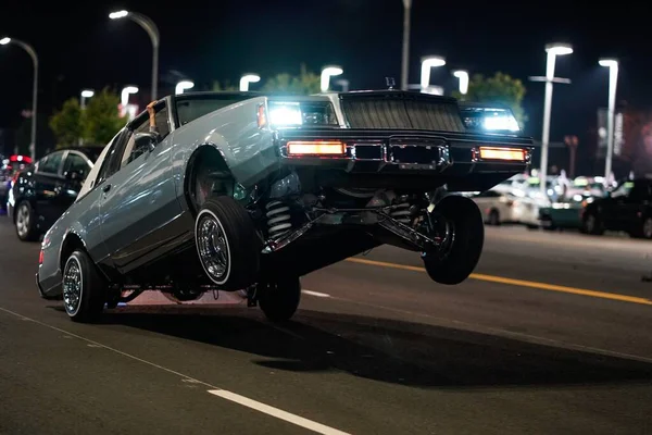 Close-up tiro de um carro retro com apenas as rodas traseiras no chão em uma rua à noite — Fotografia de Stock