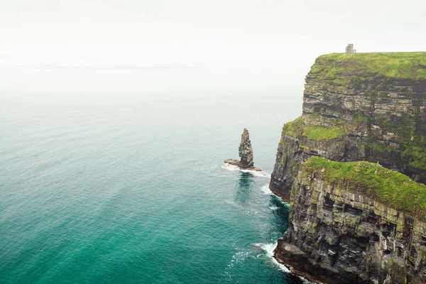 Colpo ad angolo alto mozzafiato di una scogliera verde vicino all'oceano con acqua turchese — Foto Stock