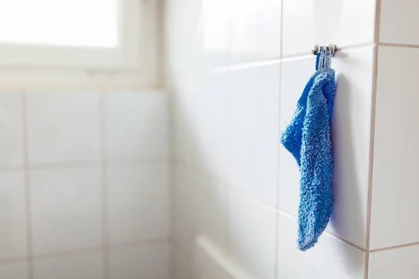 Closeup tiro de uma toalha branca em um cabide em uma parede de azulejo branco no banheiro — Fotografia de Stock