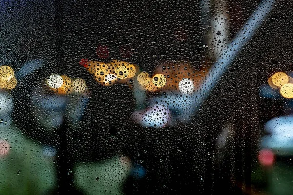 Hermosa toma de gotas de agua en una ventana durante una noche lluviosa con un fondo borroso — Foto de Stock