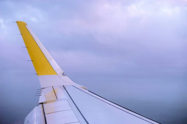 Biało-żółte skrzydło płaszczyzny z pięknymi chmurami w tle — Zdjęcie stockowe