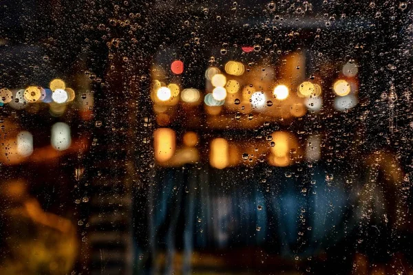 Bellissimo colpo di gocce d'acqua su una finestra durante una notte di pioggia con uno sfondo sfocato — Foto Stock