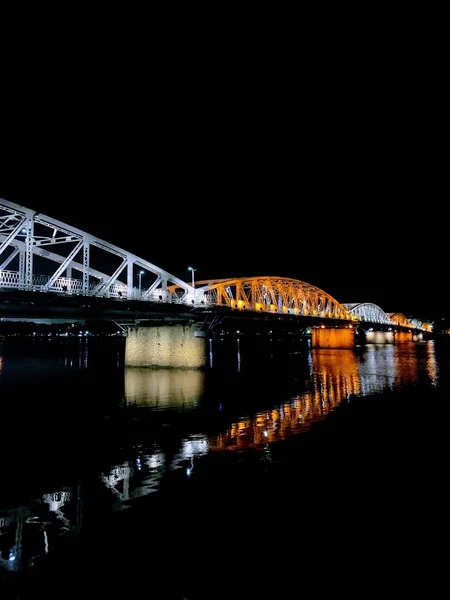 Vertical low angle shot of an illuminated bridge with yellow and white arcs with black background — Stock Photo, Image