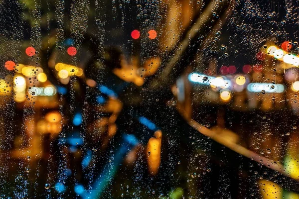 Beau plan de gouttes d'eau sur une fenêtre lors d'une nuit pluvieuse avec un fond flou — Photo