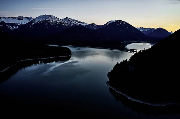 Prachtige hoge hoek opname van een rivier tussen silhouetten van heuvels en de zonsondergang op de achtergrond — Stockfoto