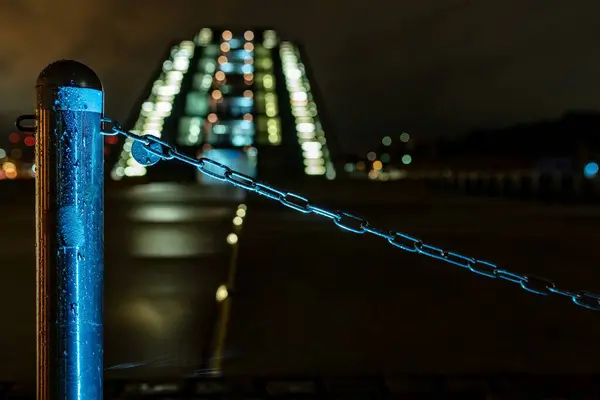 Primer plano de una cadena unida a una columna de hierro en una ciudad por la noche — Foto de Stock