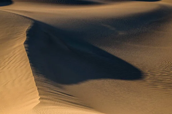 Schöne Aufnahme von Wanderwegen auf dem Wüstensand und einem großen Schatten auf dem Boden — Stockfoto