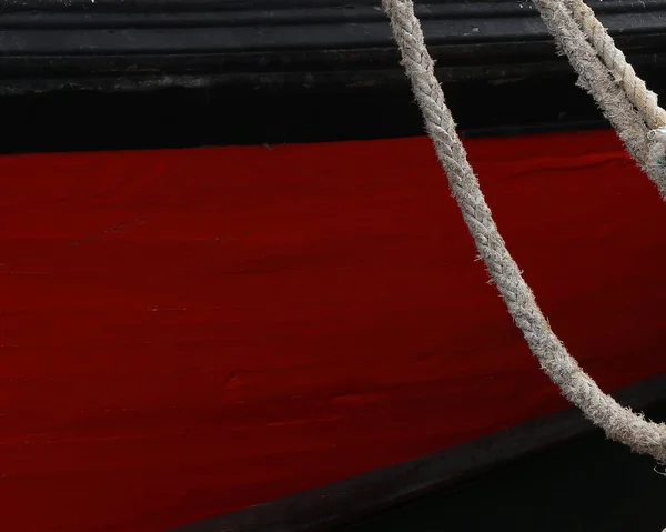 A red ship with a white knot standing at the harbor