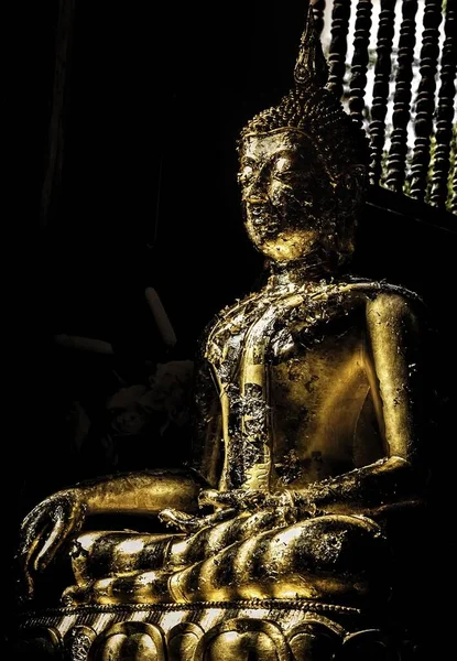 Colpo verticale di una statua di Buddha dorato all'interno di un tempio con i bellissimi raggi del sole che cadono su di esso — Foto Stock