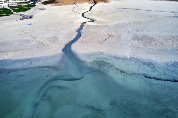 Plan grand angle d'une grosse fissure sur le rivage pierreux à côté de l'eau turquoise — Photo
