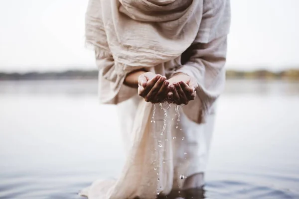 Zbliżenie samicy w biblijnym szlafroku trzymającej wodę z dłońmi — Zdjęcie stockowe